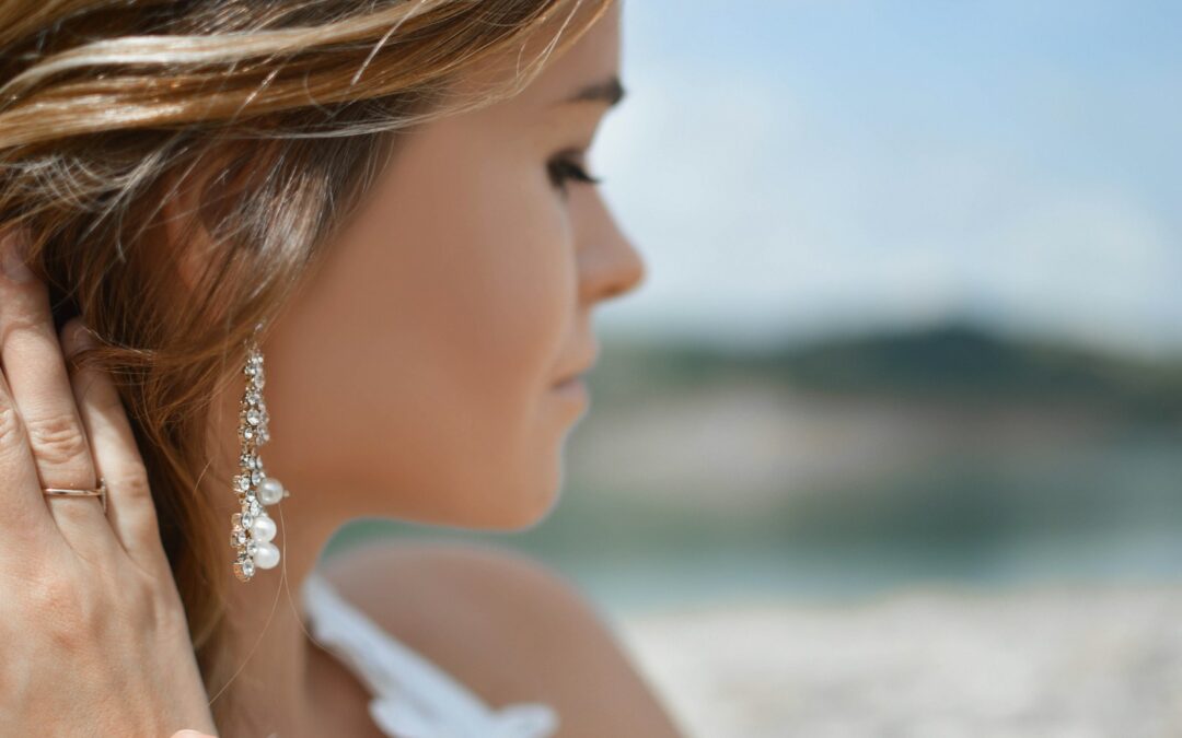 shallow focus photography of woman wearing dangling earrings holding her hair near mountain